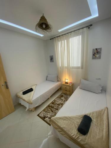 a white room with two beds and a window at Appartement Tourma in Agadir