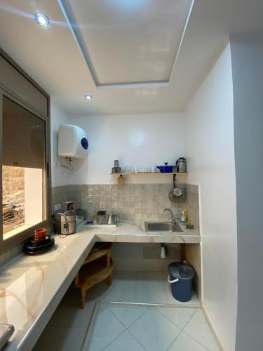 a white kitchen with a sink and a window at Appartement Tourma in Agadir