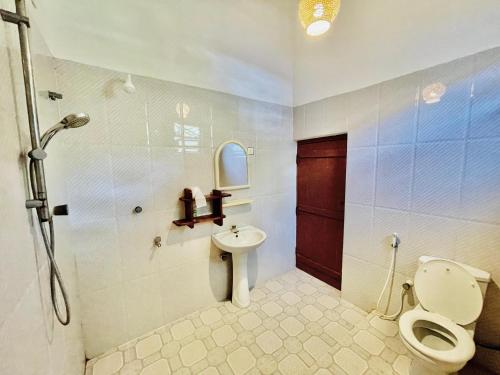 a bathroom with a toilet and a sink and a shower at Paradise Bay Hotel in Arugam Bay