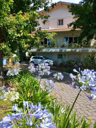 a garden with purple flowers in front of a house at Villa Do Sol Chambre d'Hôtes "Arbousiers" in Arcachon
