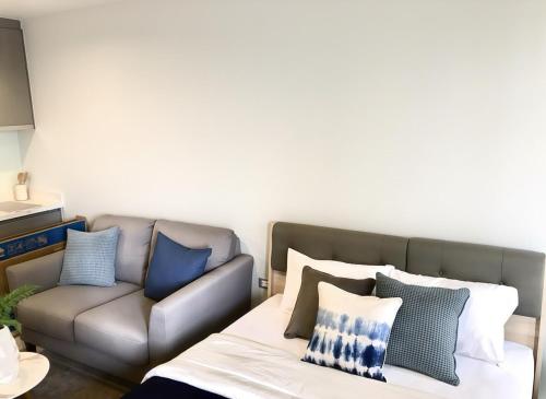 a living room with a couch and a bed and pillows at Thong Lor condo Next to BTS in Bangkok