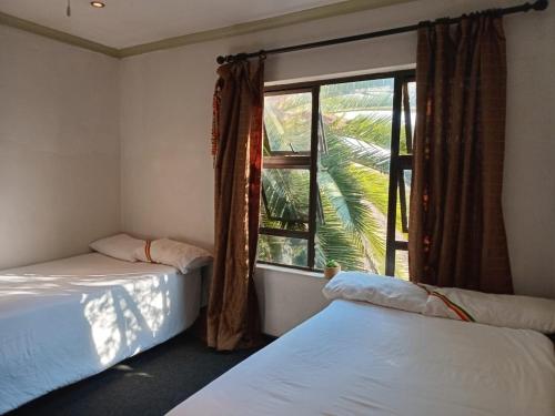 two beds in a room with a window at Afro Rasta Kumusha in Germiston