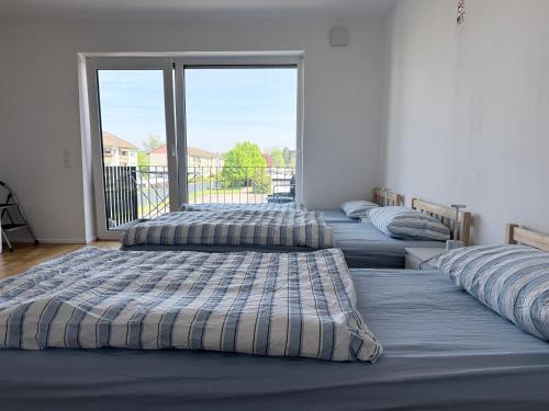 three beds lined up in a room with a window at LuxApart2Cologne in Kerpen