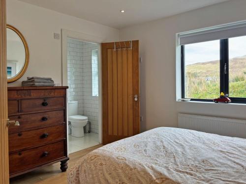 a bedroom with a bed and a mirror and a window at Cottage 503 - Leenane in Leenaun