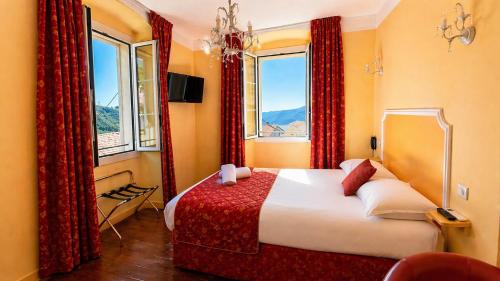 a bedroom with a large bed with red curtains at Hôtel U Palazzu & Spa - Centre du village in Venaco