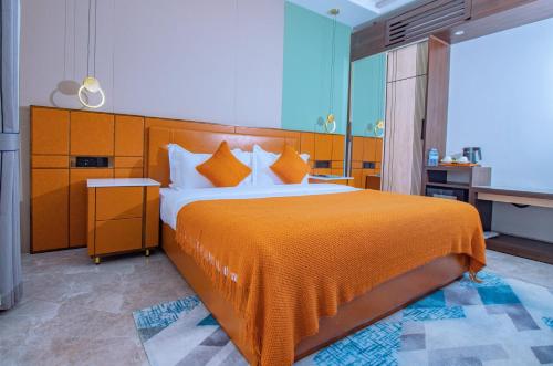 ein Schlafzimmer mit einem großen Bett und einer orangefarbenen Decke in der Unterkunft Allison Hotel in Jinja