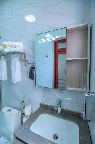 ein Badezimmer mit Waschbecken, Spiegel und Toilette in der Unterkunft Allison Hotel in Jinja