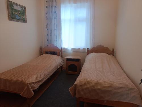 two beds in a room with a window at Zaqatala-Car riverside cottage in Zaqatala