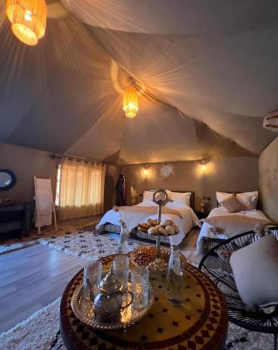 a bedroom with two beds and a table in a tent at Morocco desert camp in Merzouga