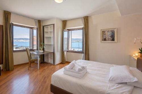 ein Schlafzimmer mit Bett, Tisch und Fenstern in der Unterkunft New Hotel Dulcinea in Muggia