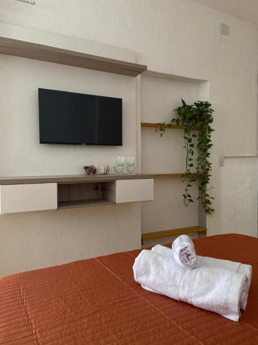 a room with a television and a towel on a bed at Casa Freitas - Suíte 2 in Extrema