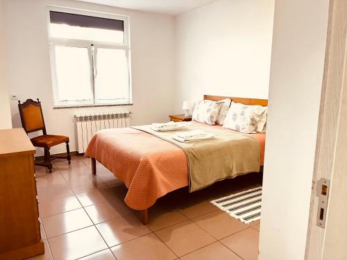 a bedroom with a bed and a chair and a window at Casa de Casarelhos - AC - BBQ - "Gerês" in Geres