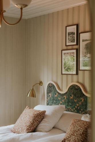 a bedroom with a bed with a headboard and pictures on the wall at Badhotellet Villa Berg in Norrtälje