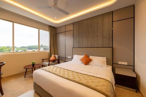 a hotel room with a large bed and a desk at Fortune Village Hotel in Kundapur