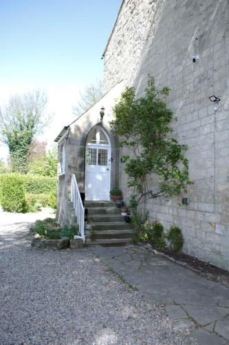 a stone building with a white door and stairs at Collins House in Knaresborough