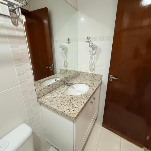 a bathroom with a sink and a mirror and a toilet at Veredas Do Rio Quente Flat Service 723 in Rio Quente
