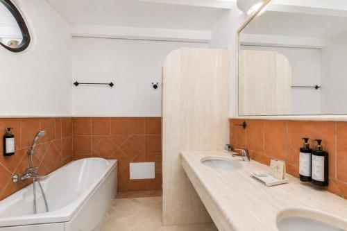 a bathroom with a tub and a sink and a bath tub at Phi Hotel Sighientu in Capitana