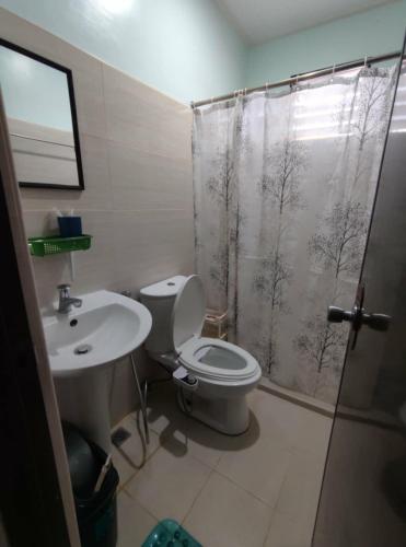 a bathroom with a toilet and a sink and a shower at GLJ Apartment in Ormoc