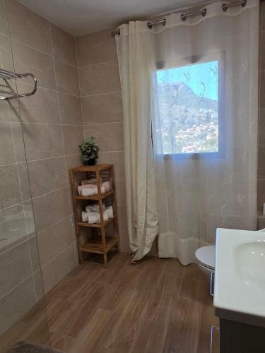 a bathroom with a shower and a toilet and a window at Apartamentos El Tosal 7E in Calpe