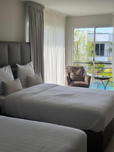 a bedroom with a bed and a chair and a window at Tucan Resort & Spa in Paramaribo
