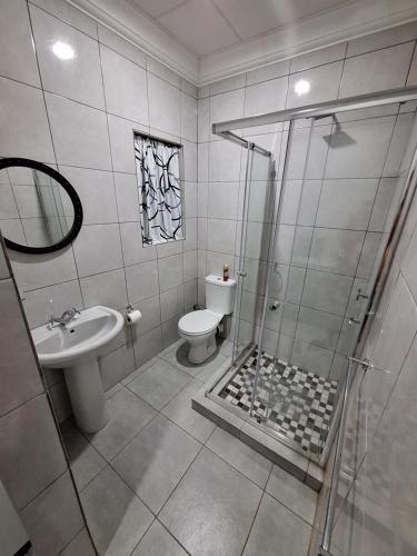 a bathroom with a shower and a toilet and a sink at Ivy Roots Guest House in Mokopane