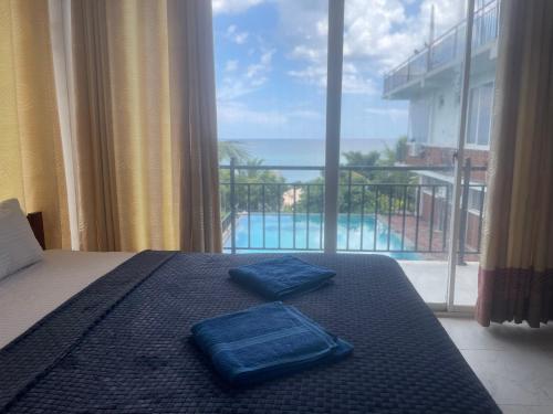 two blue towels on a bed with a large window at D & D Beach Resort in Trincomalee