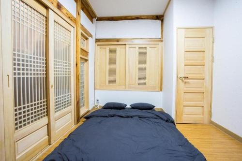 a bedroom with a large bed and two windows at Guma Modern HanokStay in Daegu