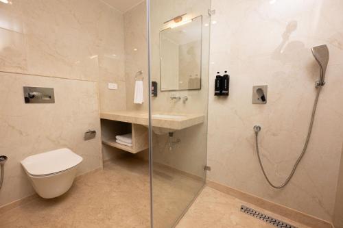 a bathroom with a shower and a toilet and a sink at Fortune Village Hotel in Kundapur