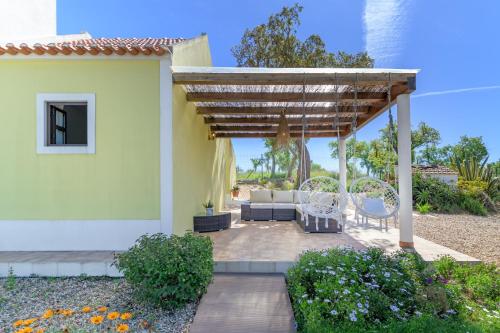 a patio with a couch under a wooden pergola at Celestial Melides Country House in Melides