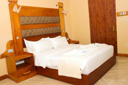 a bedroom with a large bed with a wooden headboard at Kinyuki Country Hotel in Nanyuki