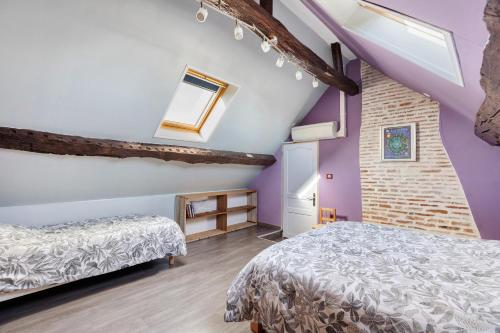 a attic bedroom with two beds and purple walls at Longère Pierre De Ronsard piscine in Rilly-sur-Loire