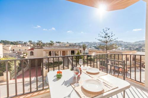 a table with wine glasses on a balcony with a view at Pool & Sea Merill Apartments Mellieha in Mellieħa