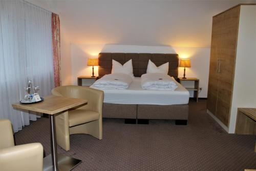 a bedroom with a bed and a table and a chair at Hotel Restaurant Weisbrod in Freinsheim