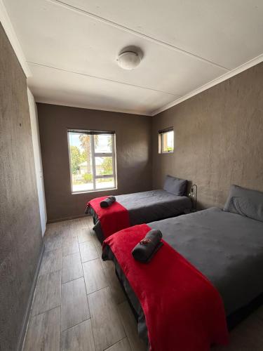 a bedroom with two beds with red sheets and a window at Marina stunning escape in Jeffreys Bay