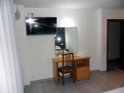 una camera con scrivania e TV appesa a un muro di Hotel Delicias a Saragozza