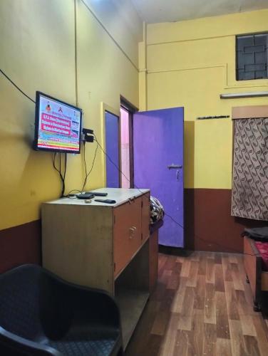 a room with a desk and a tv on a wall at Oasis Lodge in Jorhat