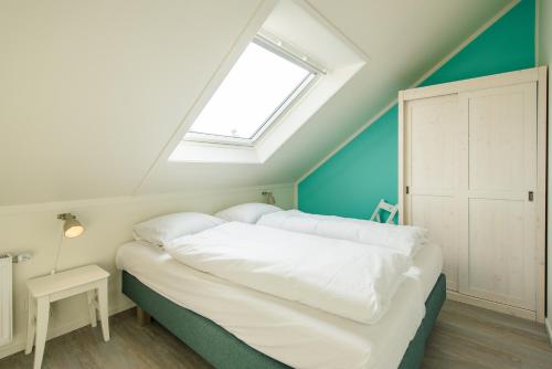 a bedroom with a large white bed with a window at Repos (6p) in Nes
