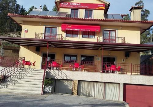 a building with a balcony with red chairs on it at Mira Serras in Vouzela