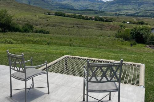 two chairs sitting on a patio with a view of a field at Cathkin Haven in Champagne Valley