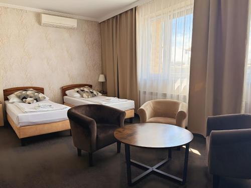 a hotel room with two beds and a table and chairs at Noclegi-Restauracja Boss in Mogilno