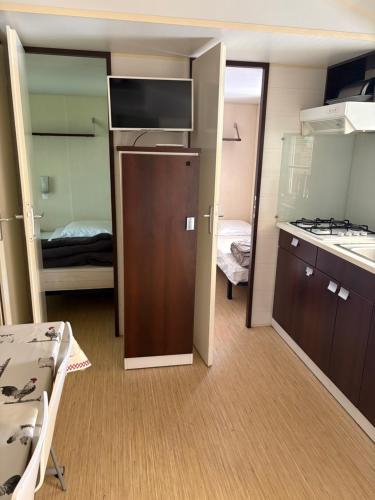 a small room with a kitchen and a room with a bed at Domaine des Iscles mobile home clim, jardinet sans vis-à-vis in La Roque-dʼAnthéron