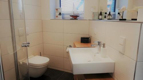 a white bathroom with a sink and a toilet at Ferienwohnung Boddenblick-Vilm in Putbus