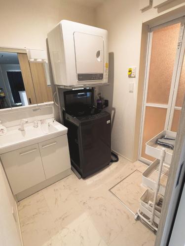 a bathroom with a tv on top of a refrigerator at 新築一棟貸切 民宿 夢 駐車場2台無料 コンビニ徒歩2分 市街地へ好アクセス in Matsuyama