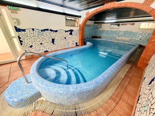 a large bath tub in a room with a tile wall at Hotel Xaine Park in Lloret de Mar