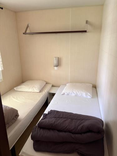 two beds in a small room withermottermottermott at Domaine des Iscles mobile home clim, jardinet sans vis-à-vis in La Roque-dʼAnthéron