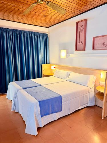 a bedroom with two beds and blue curtains at Hotel Xaine Park in Lloret de Mar