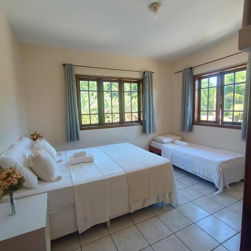 a bedroom with two beds and two windows at Mestre Lord Apart Hotel 300m Praia Taperapuã by La Vem Férias in Porto Seguro