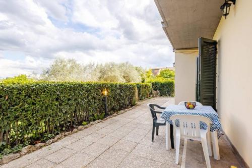 a table and chairs on a patio with a hedge at Tuscan Sunrise Home in Monteriggioni