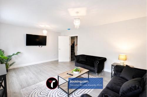 a living room with a couch and a tv on a wall at Spacious 4 Bedroom By Tara Stays Short Lets & Serviced Accommodation Aldershot With Free WiFi & Garden in Aldershot