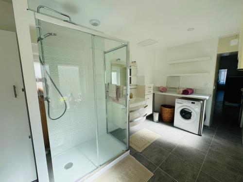 a bathroom with a shower and a washing machine at La Maison du Chenal in Gravelines